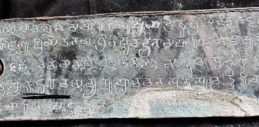 A rectangular copper leaf with five lines of incised Telugu-Kannada script and a circular binding hole at the left.