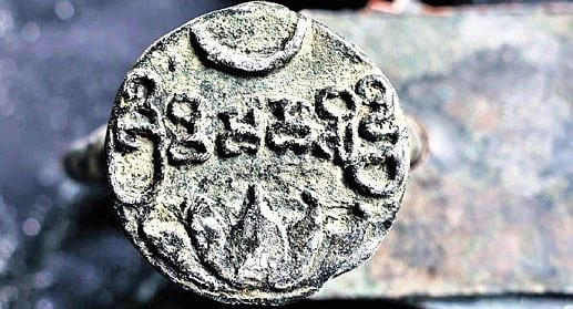 Circular metal seal of the Pune plates: a crescent above a line of raised script and a lotus below, on a plain field.