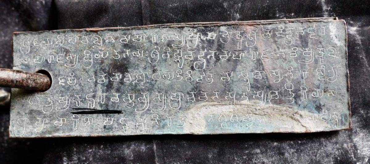 A copper plate on a ring, with five lines of script and one passage underlined in the source photograph.